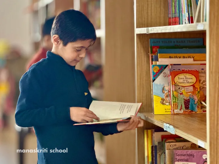 Student reading a book in the Kitabghar library at Manaskriti School Faridabad